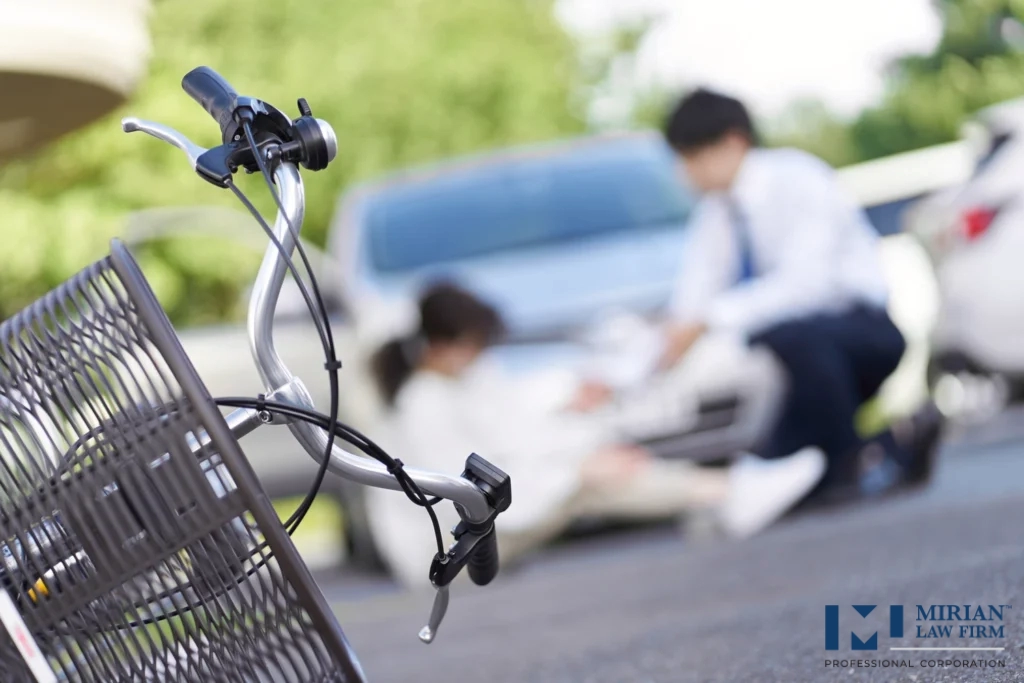 A bicycle girl hit by a car in an accident. She is injured and sat on the floor.